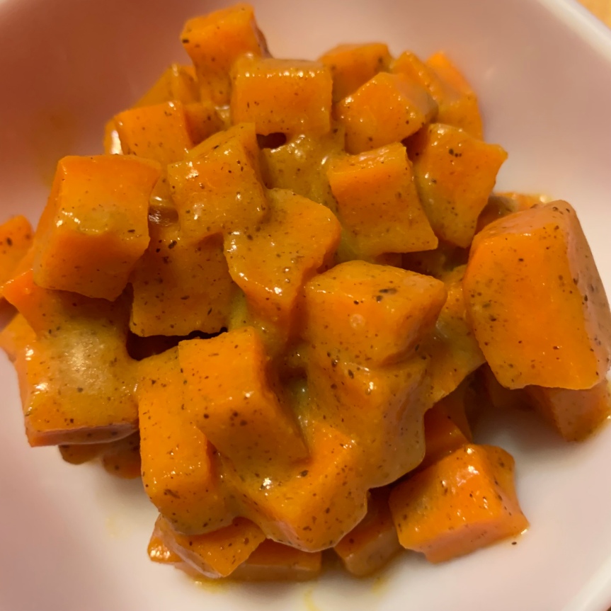 A pile of small to medium diced sweet potato bound with orange spice glaze.